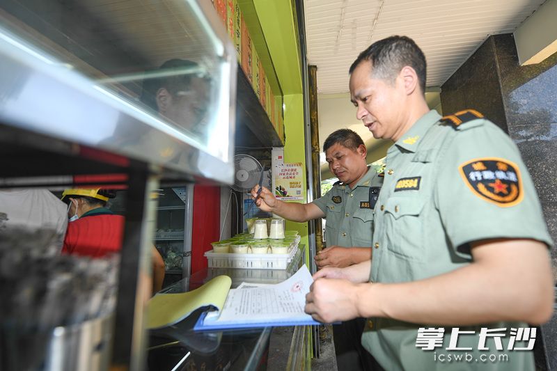 在岳麓區(qū)天馬路一處門店，城管執(zhí)法人員正在耐心勸說店主將店外經(jīng)營的柜子撤進門店,。長沙晚報記者 黃啟晴 攝