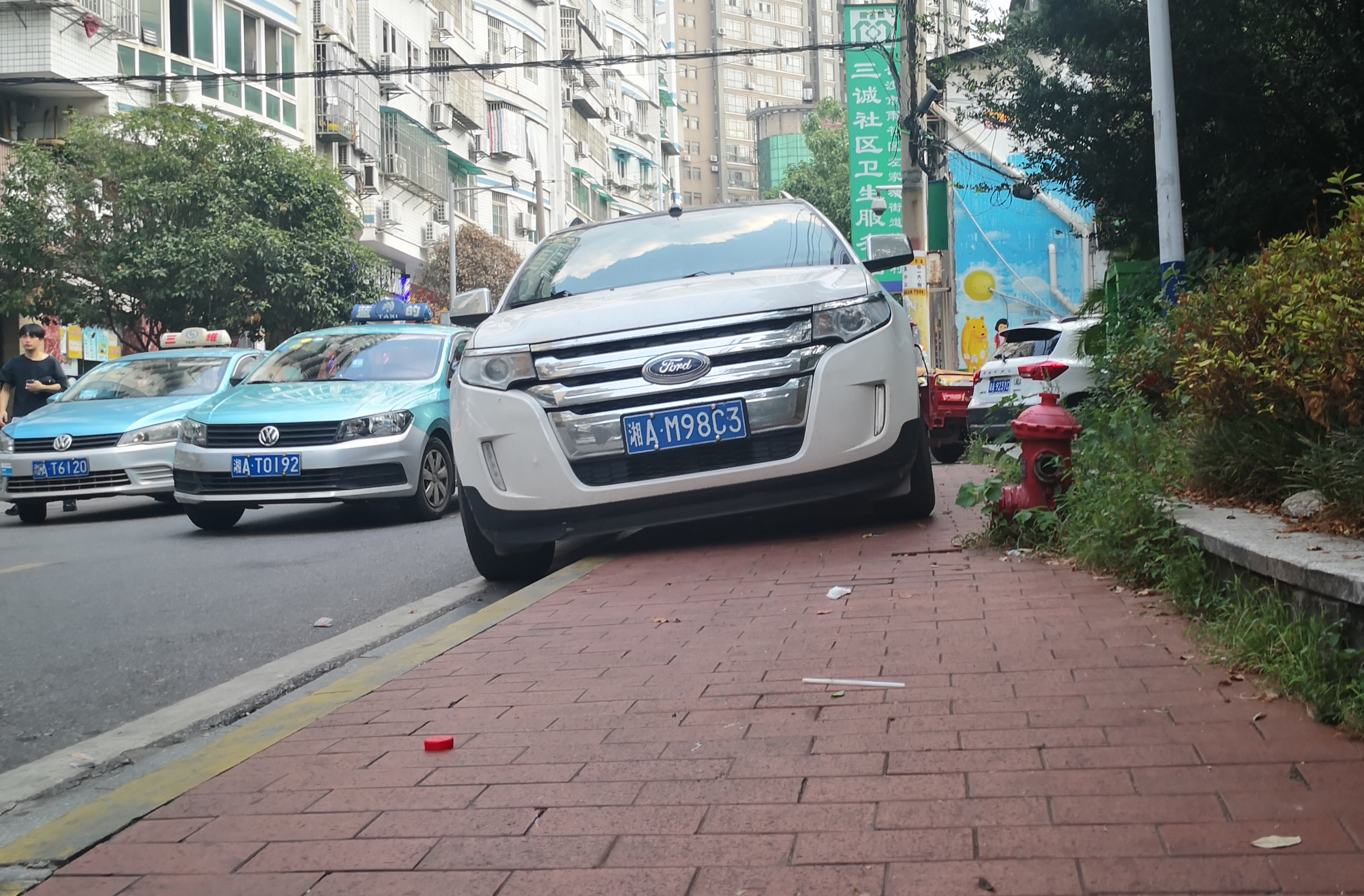 桂花樹街路邊人行道上,，一輛私家車“騎”在路邊停放著,。