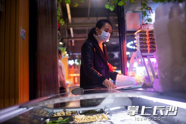 王曼在社區(qū)的商鋪里,，查看店鋪的消毒衛(wèi)生情況,。