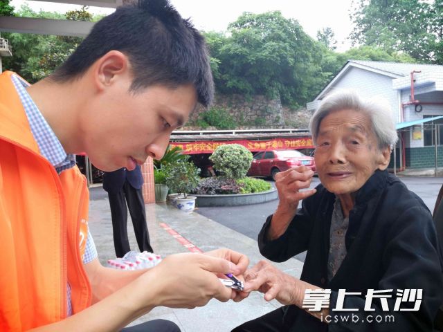 志愿者為老人修剪手指甲,。長沙晚報(bào)全媒體記者 賀文兵 攝