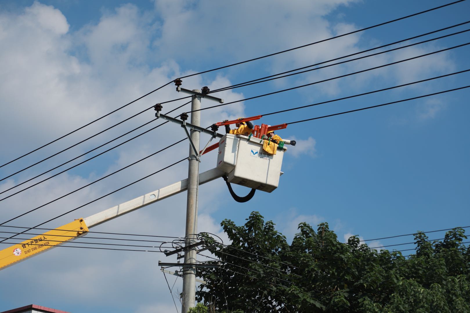 高溫下，國網長沙帶電作業(yè)中心在長沙縣黃江公路附近對10千伏梨江線瓷瓶故障進行帶電搶修,。通訊員  鄧梁攝