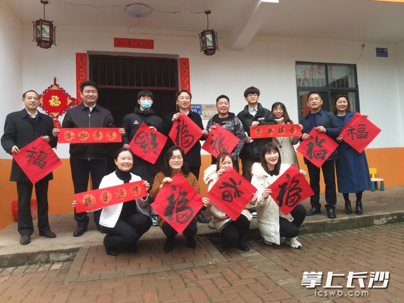 舉著福字和對(duì)聯(lián),，扶貧干部,、志愿者、脫貧戶和大學(xué)生都很開心,。長(zhǎng)沙晚報(bào)全媒體記者 王斌 攝