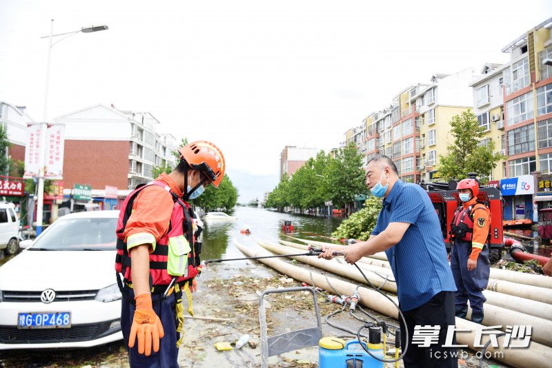 排澇現(xiàn)場,，崔雯元為在積水中作業(yè)的消防員消毒,。長沙晚報(bào)全媒體記者 劉琦 攝