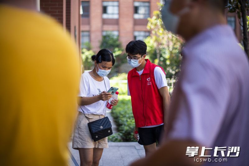 上午10點(diǎn),，在開福區(qū)一中核酸檢測點(diǎn),，18歲的準(zhǔn)大學(xué)生李紅生在指導(dǎo)市民用手機(jī)進(jìn)行核酸登記。