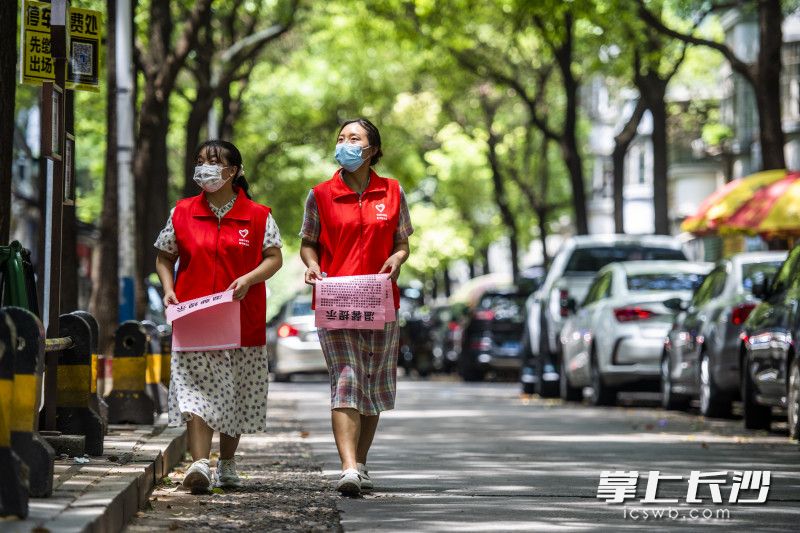 志愿者羅娟（左）和張倩倩（右）在社區(qū)內(nèi)進(jìn)行防治疫情宣傳提示的粘貼。羅娟是98年出生,，倩倩是99年出生,，疫情發(fā)生以來，她倆第一時間參與志愿服務(wù),，協(xié)助街道開展人員勸導(dǎo)等工作,，一天時間走了2萬多步，要喝7-8瓶水,。 