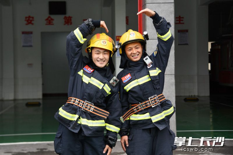 外賣小哥李建培（左）與消防員比拼穿滅火防護(hù)服后，合影留念,。