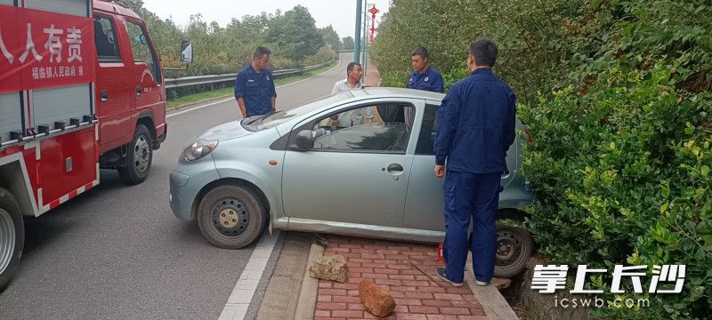 消防員一邊抬車,，一邊往后輪下方墊磚塊和石塊。長沙晚報通訊員 胡宇波 供圖