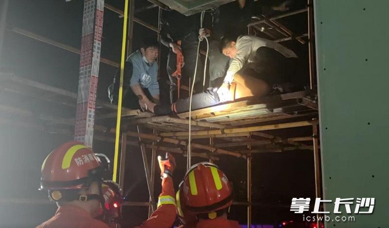 現(xiàn)場(chǎng),，消防員與工地工人合力將醉酒男子轉(zhuǎn)移至安全地帶。長(zhǎng)沙晚報(bào)通訊員 劉姿 供圖