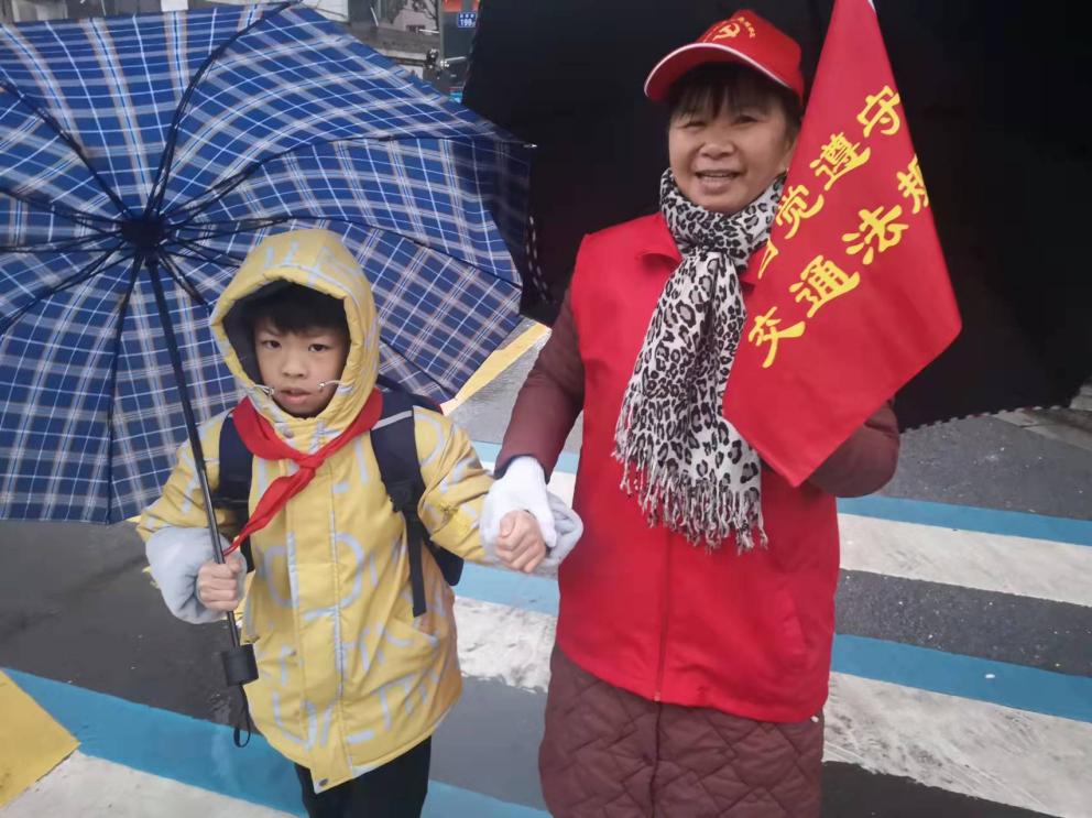 “金姐桂哥”志愿者護(hù)送學(xué)生過馬路。長沙晚報(bào)通訊員 周柔 供圖