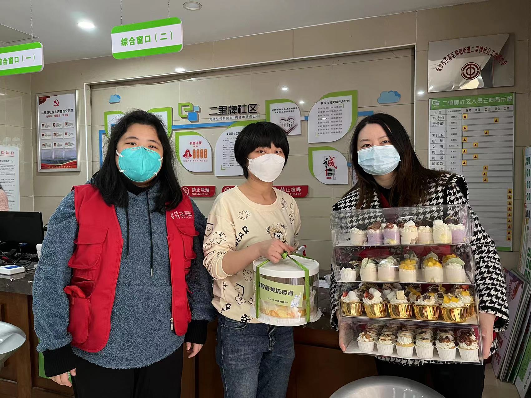 王莉丹（中穿黃色衣服者）將連夜趕制的1000份愛心小蛋糕，送到朝陽街道一線戰(zhàn)“疫”者手中,。均為長沙晚報(bào)通訊員 彭汀汀攝