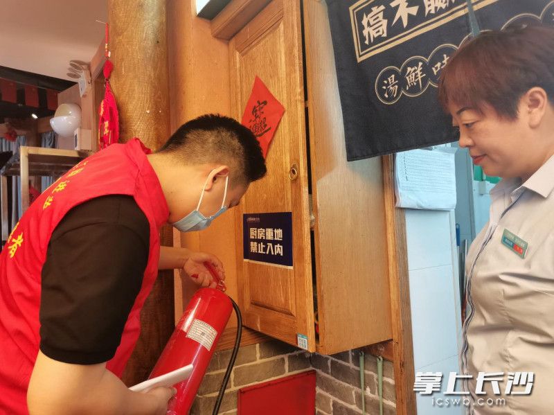 網(wǎng)格管家正在查看門店滅火器,，督促門店更新巡查記錄。長沙晚報(bào)全媒體記者 王斌 攝