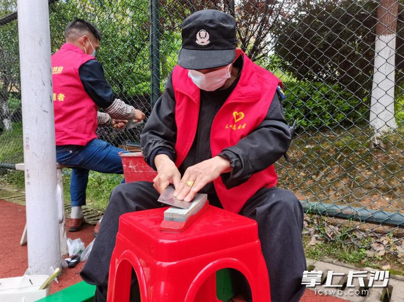 “紅色物業(yè)”志愿者正在幫助居民磨刀,。長沙晚報通訊員 徐玲 供圖