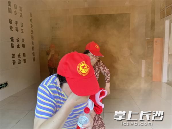 黨員志愿者捂住口鼻從消防通道模擬逃生。