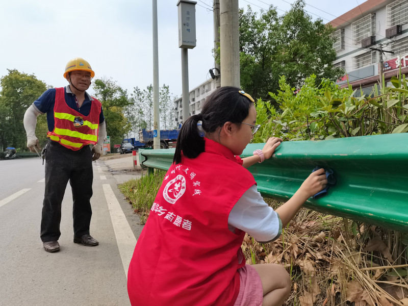 寧鄉(xiāng)市志愿者在清潔道路圍欄,。