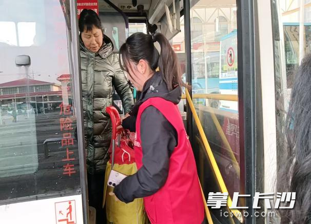 一名青年志愿者幫旅客把行李送上車,。均為長沙晚報通訊員 黃盈 供圖