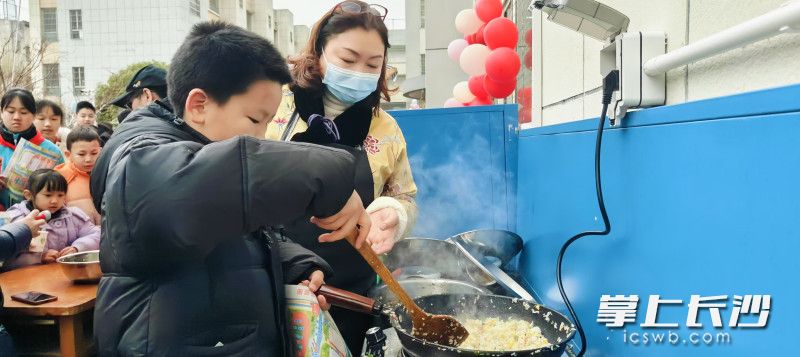 從校長(zhǎng)媽媽手里拿過(guò)鍋鏟制作揚(yáng)州炒飯。  長(zhǎng)沙晚報(bào)通訊員 鄭薇 趙娟 攝