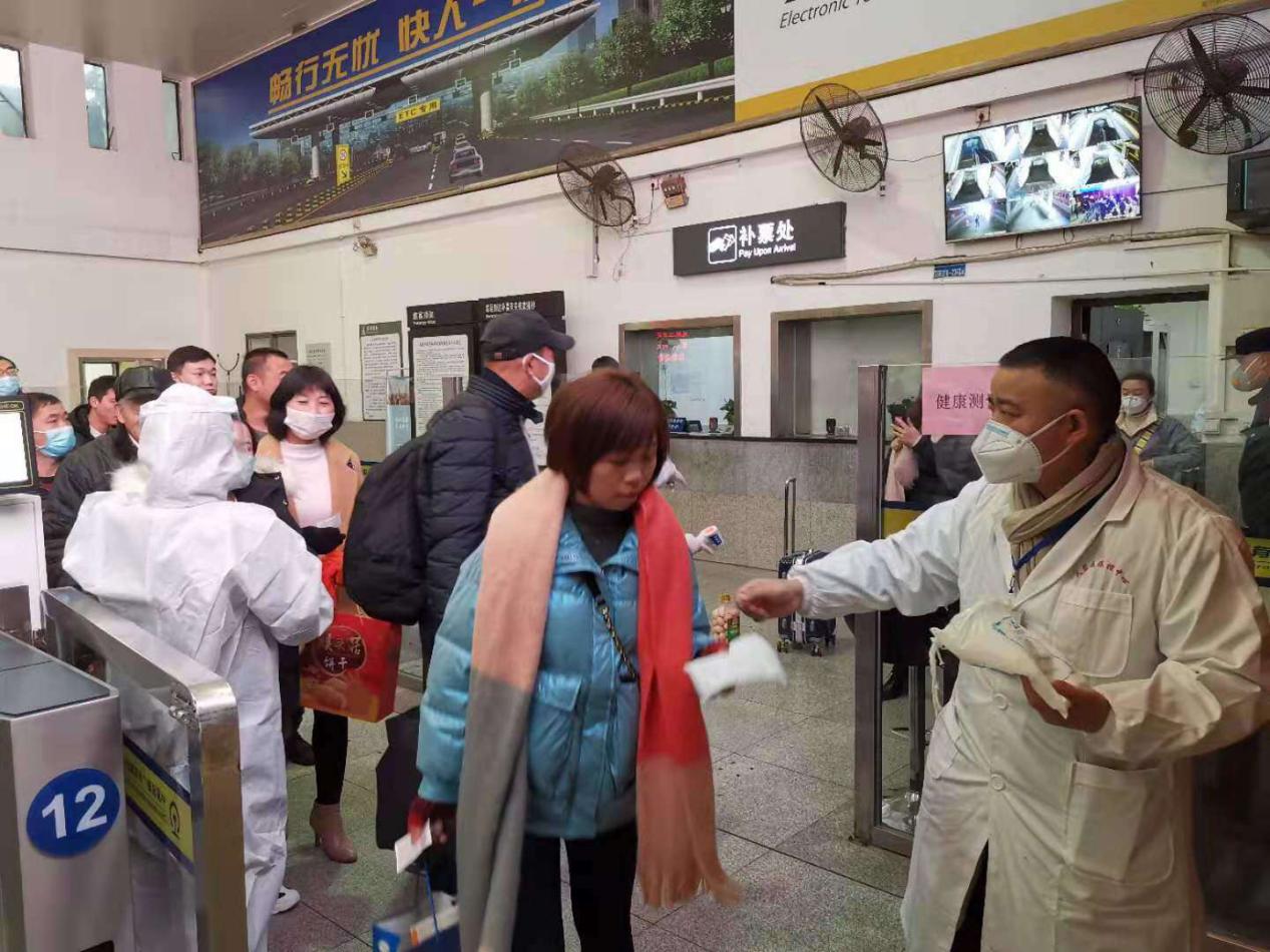 圖為陳怡軍在為火車(chē)站旅客發(fā)放口罩