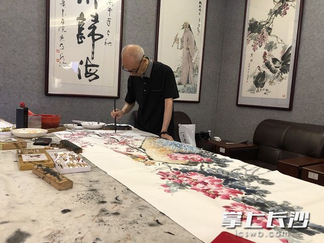 86歲的熊大炎老先生站立兩個鐘頭,，完成了一幅花鳥畫作品,，名為《錦上添花》。畫中,，花朵隨意綻放,，活靈活現(xiàn)的鳥兒俏皮又可愛。陳丹妮  攝