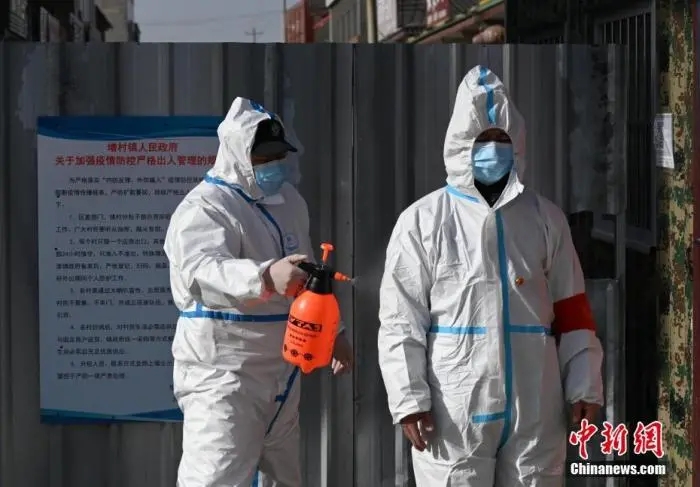 圖為警員為從小果莊村出來的防疫工作人員消毒,。中新社記者 翟羽佳 攝