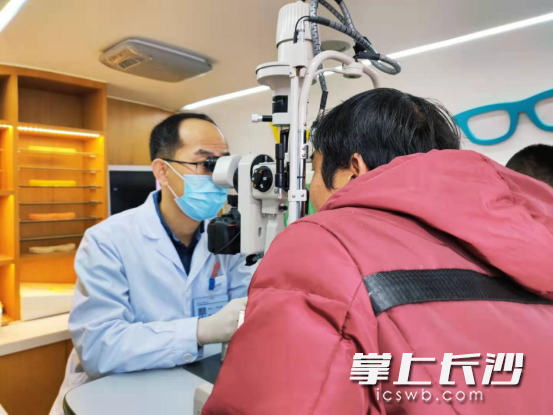 周增超在流動服務車上為鄧先生做眼部復查。