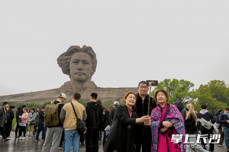 游客與偉人雕塑合影,。