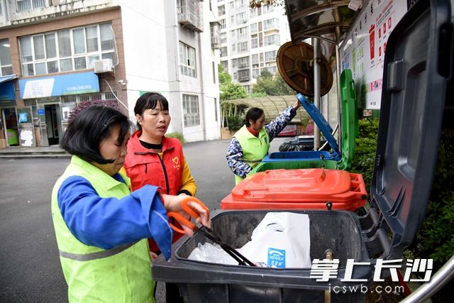 麓谷街道錦繡社區(qū)麓山潤(rùn)城小區(qū)志愿者在桶邊檢查垃圾是否投放準(zhǔn)確。