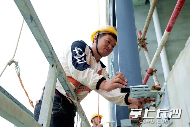 吊籃工陶汝江正在細(xì)致地安裝穿孔鋁板,。
