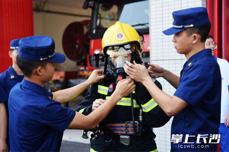 在消防員的幫助下，一名學(xué)生體驗穿滅火戰(zhàn)斗服,，佩戴空氣呼吸器,。