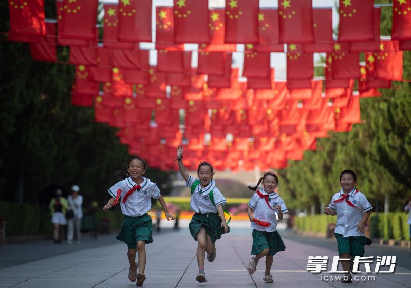 烈士公園南門廣場，幾位學(xué)生正開心的奔跑在紅旗下,。長沙晚報全媒體記者 鄒麟 攝