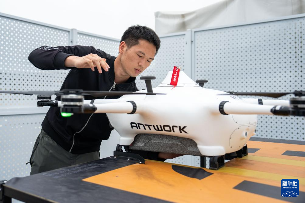 The photo shows a safety staffer placing goods into a UAV on the rooftop of Wuyue Square in Changsha County. (Photo/Chen Sihan, Xinhua News Agency)