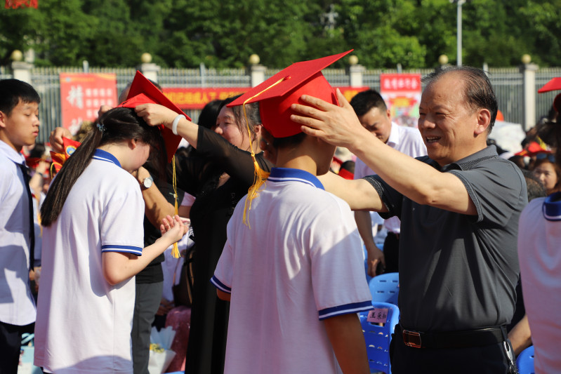 金海教育集團董事長楊建新給學生戴成人帽,。