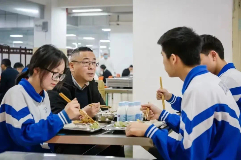 學校推行陪餐制，保證食堂飲食質量,。圖為長沙市實驗中學黨委書記肖建軍（左二）跟學生一起進餐,。資料圖片